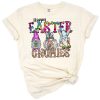 Three gnomes with bunny ears surrounded by watercolor eggs, glitter accents, and colorful tie dye patterns.