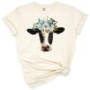 A hand drawn cow with a bird perched on its head and watercolor flowers around its neck.