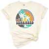 A retro vintage design of a sunkissed sun with distressed palm trees and summer style.