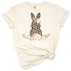 A cheerful Easter bunny with leopard spots surrounded by blush floral elements.