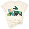 A vintage tractor and truck filled with colorful Easter eggs in a festive spring scene.