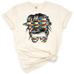 A girl with a messy bun hairstyle, sunglasses, and an autism awareness bow in her hair.