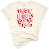 A retro-inspired artwork with the phrase 'Thick Thighs Love Vibes' surrounded by playful Valentine-themed accents.